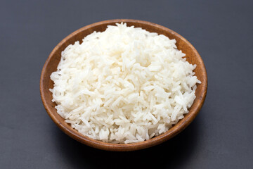 Fototapeta na wymiar Dish of rice in wooden bowl on dark background.