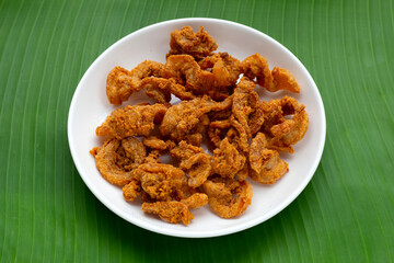 Fried crispy pork belly recipe in white plate on banana leaf