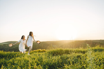 Portrait of two sisters in white dresses with long hair in a field