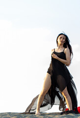 Girl with black fluttering cloth dancing on the sand dune