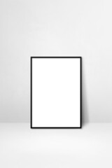 Black picture frame leaning on a white wall