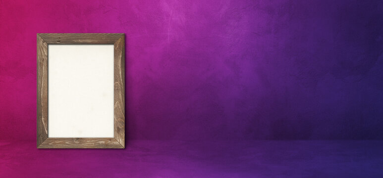 Wooden picture frame leaning on a purple wall. Horizontal banner