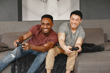 Two friends playing Playstation in the living room