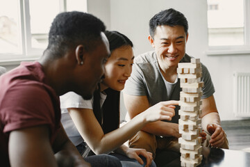 Three friends playing jenga in the living room