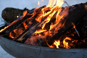 Burning firewood in the winter snow garden.Burning firewood background.Flames and sparks