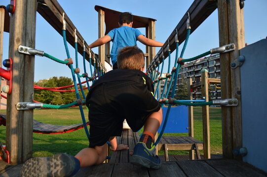 two children playing on a rope toy in a playground