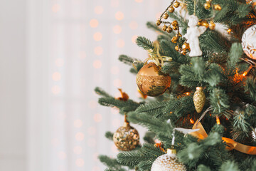 Decorated Christmas tree in golden and white toys with the lights bokeh textured background