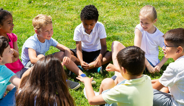 Group of elementary school children chatting on the green lawn. High quality photo