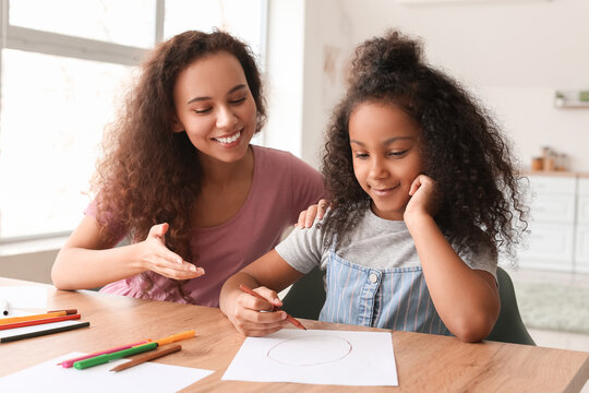 African-American little girl with her mother drawing at home