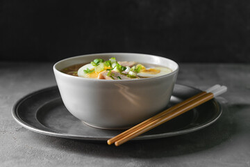 Tasty Chinese soup with chicken in bowl on dark background