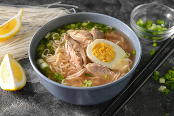 Tasty Chinese soup with chicken in bowl on dark background