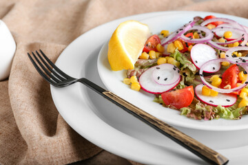 Plate of fresh salad with Lollo Rosso lettuce on table