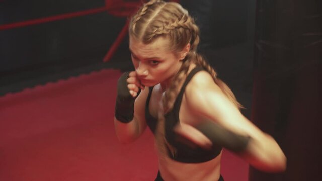 Female fighter trains his punches and defense in the boxing gym, female trains a series of punches, front view.