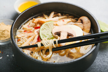 Bowl of tasty Thai chicken soup on table, closeup