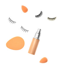 Bottle of tonal foundation with makeup sponges ad false eyelashes on white background