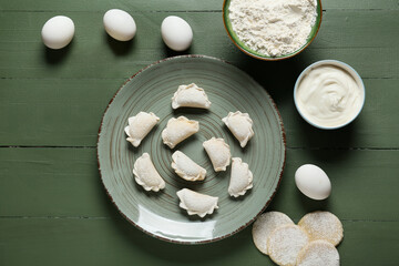Composition with raw dumplings on color wooden background