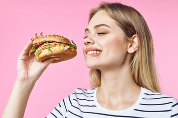woman in striped t-shirt hamburger delicious sandwich snack pink background