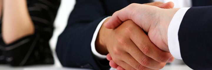 Man in suit shake hand as hello in office closeup