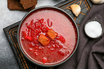 Bowl of tasty borscht and salt on grunge background