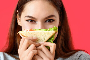 Young woman with tasty sandwich on color background