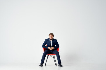 man in suit sitting on red chairs emotions office light background