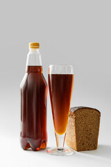 Glass and bottle of fresh kvass on light background