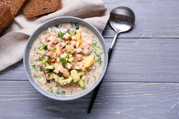 Bowl with tasty okroshka and bread on dark wooden background