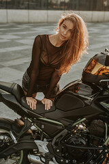 Fototapeta na wymiar Seductive woman with brown hairs and dark bike outside