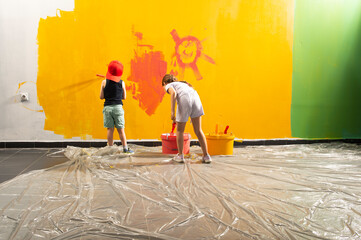 A boy and a girl paints a wall at home