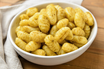 Bowl with tasty pesto gnocchi on table, closeup