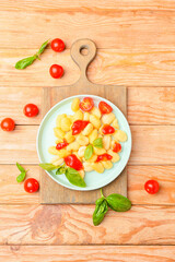 Delicious gnocchi with tomato sauce in plate on wooden background