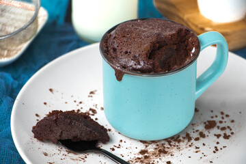 mugcake is microwaved. Homemade cupcake in a mug is on a plate. Chocolate brownie mug cake. Easy cooking concept, microwave baking. muffin chocolate. ingredients, eggs, milk, cocoa.