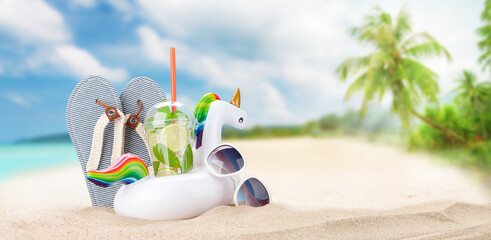 Summer sea landscape with mojito cocktail, inflatable unicorn, sunglasses and flip-flops