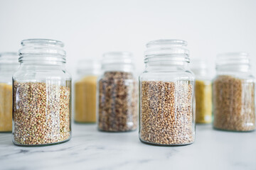clear pantry jars with different types of grains in them including quinoa rice buckwheat couscous...