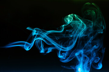 Abstract colored smoke moves on dark background. Wallpaper. Personal vaporizers fragrant steam. Concept of alternative non-nicotine smoking. E-cigarette. Texture. Design elements.