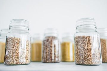 clear pantry jars with different types of grains in them including quinoa rice buckwheat couscous and barley, simple ingredients concept