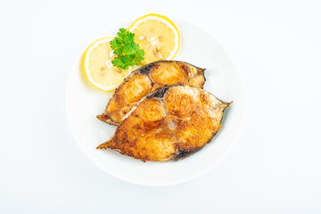 Pan-fried mackerel pieces on a plate on white background