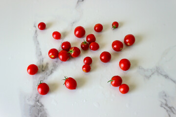 Small fresh cherry tomatoes on a white  kitchen table. Concept- fresh organic vegetables, healthy food from garden.