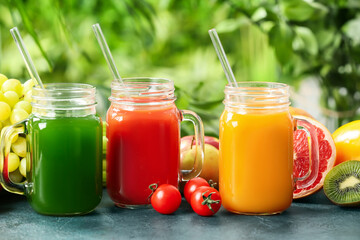 Fototapeta na wymiar Mason jars with healthy juice, fruits and vegetables on table outdoors