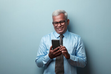 Smiling businessman of Indian ethnicity looking at his mobile phone