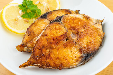 Pan-fried mackerel pieces on a plate on white background