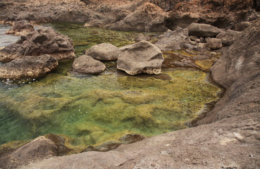Naklejka na ściany i meble Gran Canaria, calm natural seawater pools in under the steep cliffs of the north coast and separated from the ocean by volcanic rocks, Sardina del Norte area