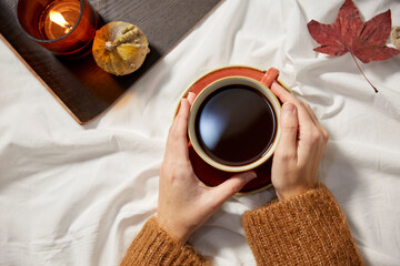 people, season and leisure concept - hands of woman with cup of black coffee in autumn