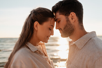 leisure, relationships and people concept - happy couple with closed eyes on summer beach