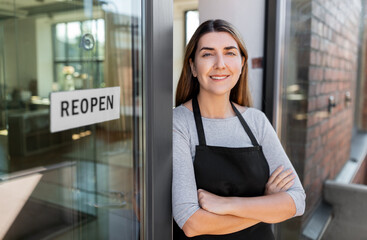 small business, reopening and service concept - happy smiling woman with reopen banner on window or door glass
