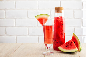 Watermelon drink in a glass with fruit decor and a bottle with berry slices on white background with copy space. Fresh red lemonade to drink during summer day. Cooling beverage