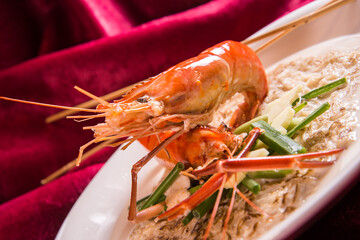 braised fried egg eefu noodle mee with big tiger prawn and lobster in thick cheese soy gravy in plate on red cloth table asian cafe cuisine Chinese restaurant banquet halal food menu