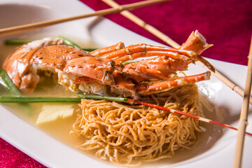 braised fried egg noodle mee with big tiger prawn and lobster in thick soy gravy on red background asian halal banquet menu