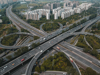 Top up aerial drone view of elevated road and traffic junctions in Chinese metropolis city during sunny day golden hour. Modern construction design of traffic ways to avoid traffic jams. Few vehicles.