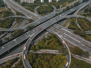 Top up aerial drone view of elevated road and traffic junctions in Chinese metropolis city during sunny day golden hour. Modern construction design of traffic ways to avoid traffic jams. Few vehicles.